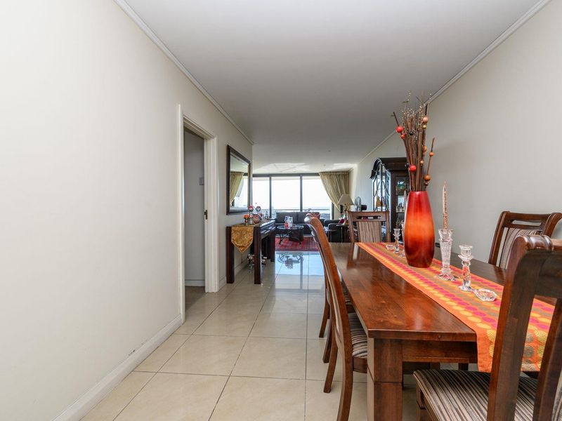 Open plan dining and living area featuring neutral tiled flooring and large sliding glass doors leading to an outdoor space.