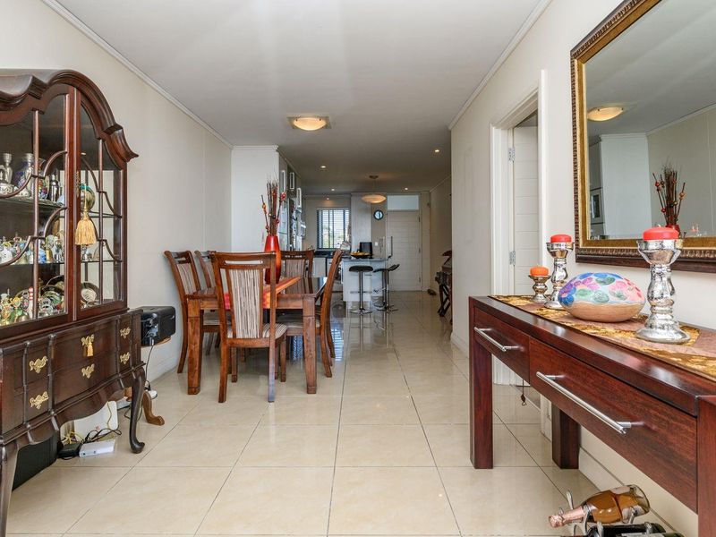 Spacious open-plan living and dining area featuring polished tile flooring, recessed lighting, and a seamless transition into the modern kitchen space.