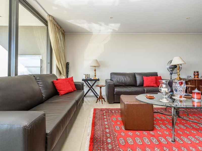 A bright living room featuring tiled flooring and a large sliding glass door providing access to an outdoor balcony area.