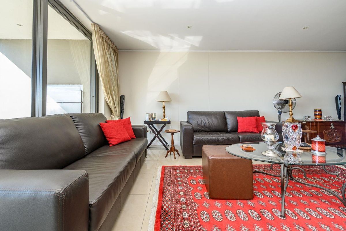 A bright living room featuring tiled flooring and a large sliding glass door providing access to an outdoor balcony area.