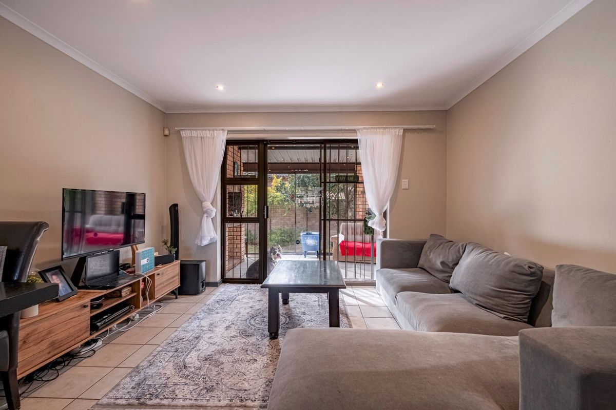 A comfortable living room featuring tiled flooring and sliding glass doors that provide direct access to the rear patio area.