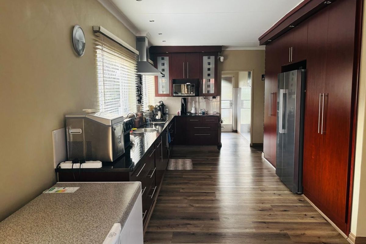 A functional kitchen featuring dark wood cabinetry, granite countertops, integrated storage, and wood-look flooring, leading to a rear access point.