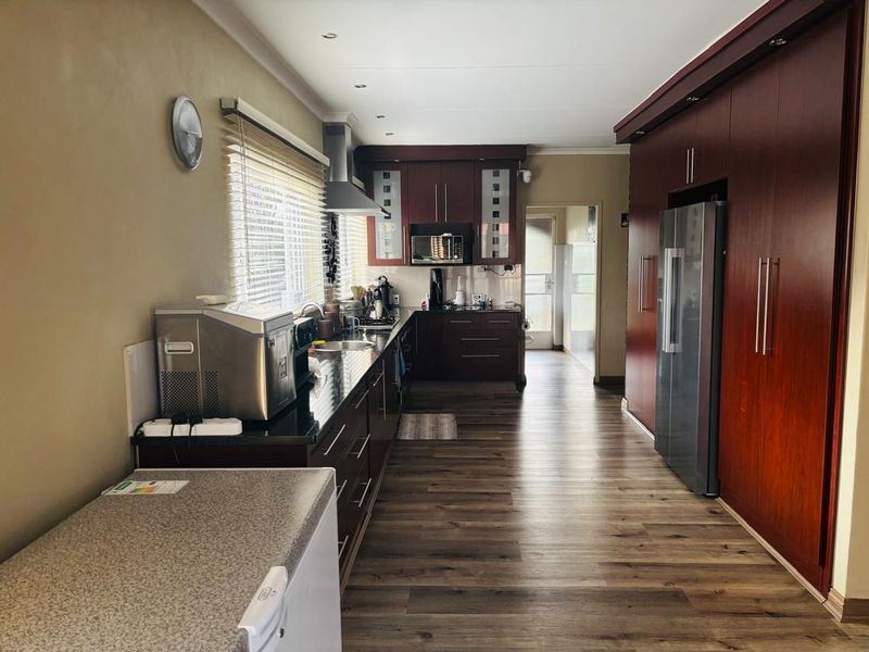 A functional kitchen featuring dark wood cabinetry, granite countertops, integrated storage, and wood-look flooring, leading to a rear access point.