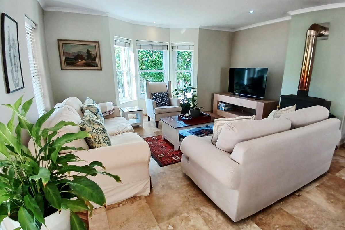 A comfortable living room featuring a bay window, tiled flooring, and a built-in fireplace with a metal flue.