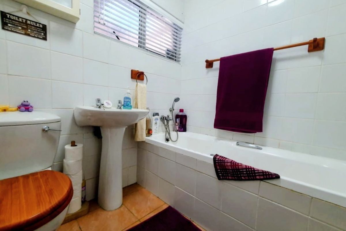 A functional bathroom featuring a white pedestal sink, a standard bathtub with shower mixer, and tiled wall finishes.
