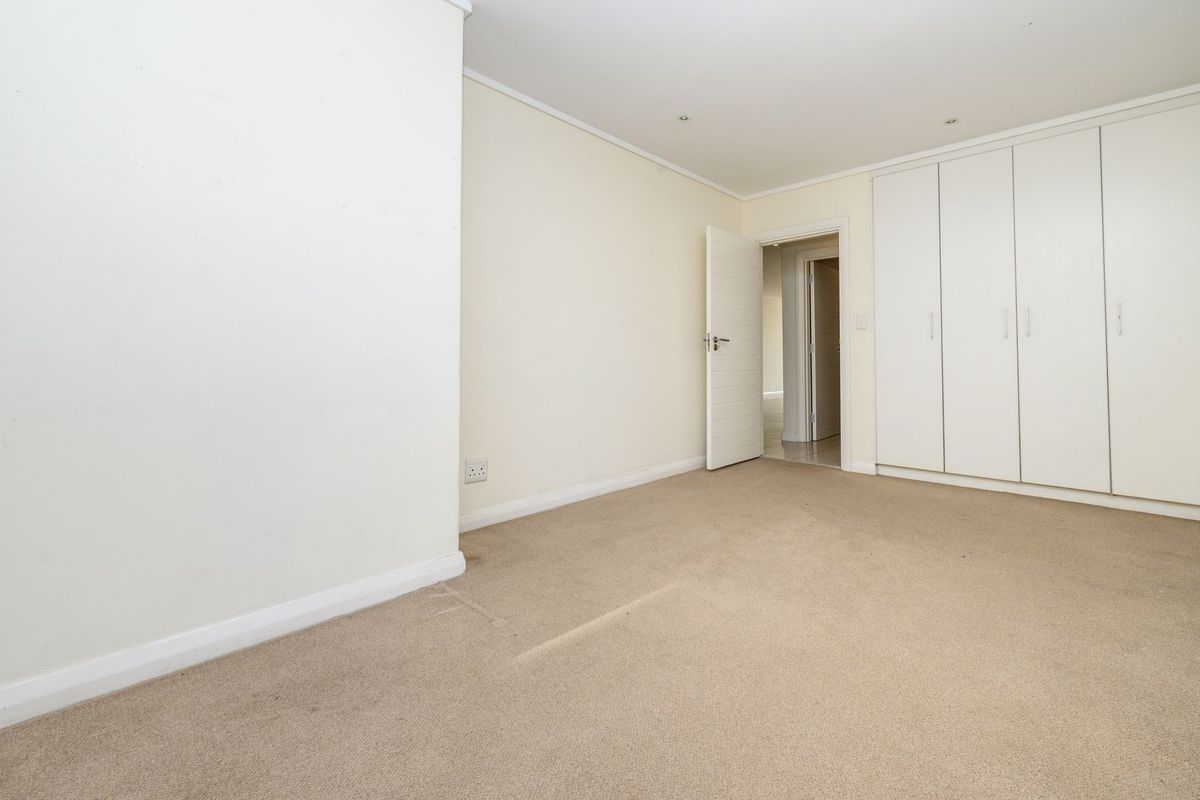 An empty bedroom featuring neutral walls, carpeted flooring, and built-in cupboards with ample storage space.