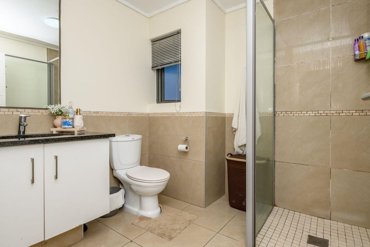 A functional bathroom featuring a vanity with granite countertop, a toilet, and a walk-in shower with glass enclosure and tiled finishes.