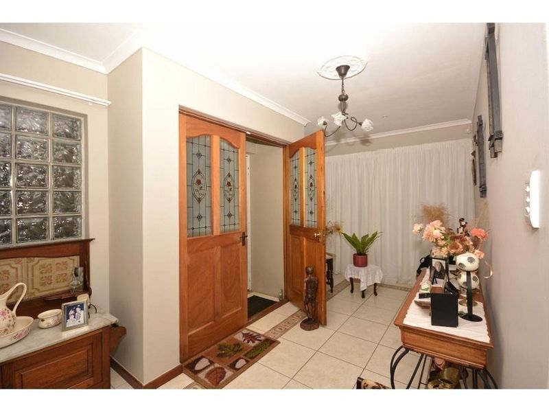 Welcoming entrance hall featuring ceramic floor tiles, decorative ceiling rose, and timber double doors with leadlight glass inserts.