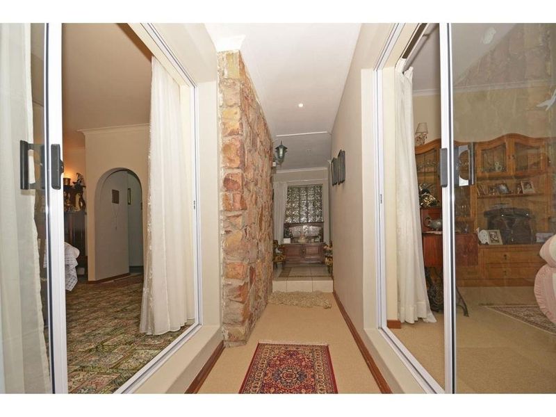 A central hallway featuring a rustic stone accent wall, flanked by sliding glass doors that provide views into the adjacent living areas.