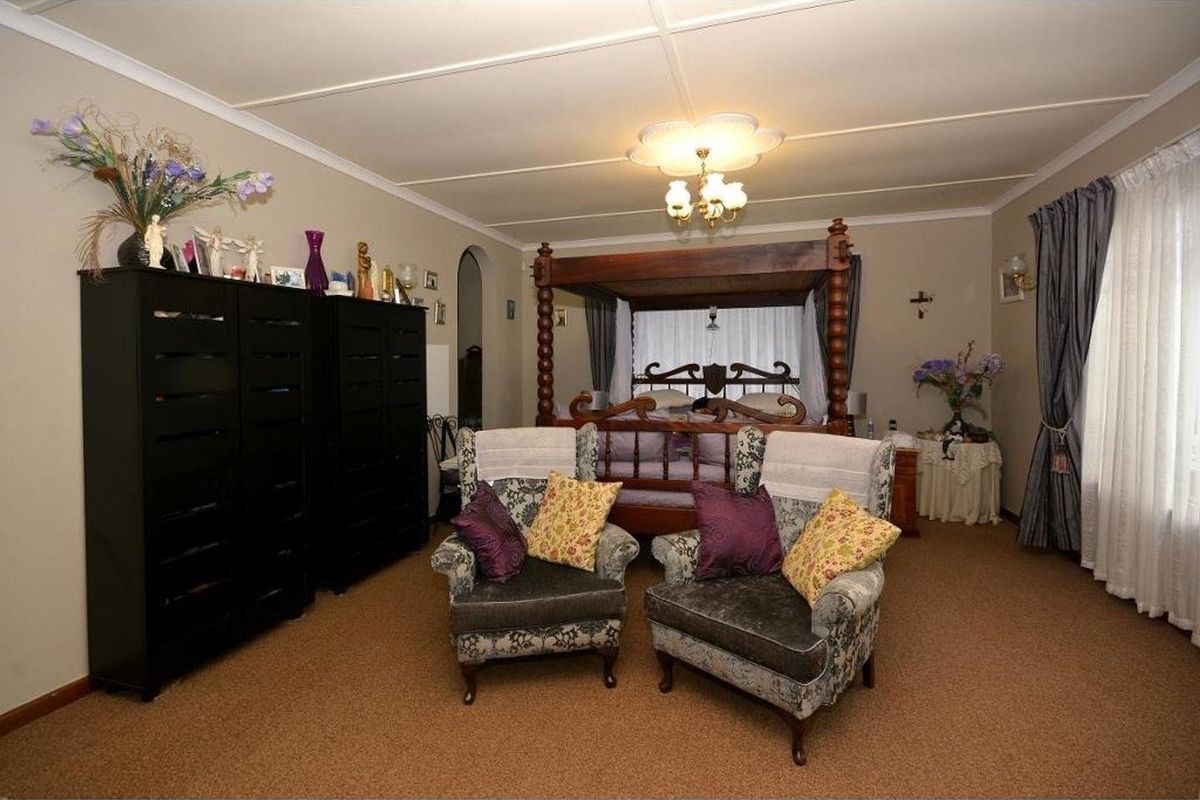 A spacious bedroom featuring neutral wall tones, carpeted flooring, and decorative ceiling detailing.