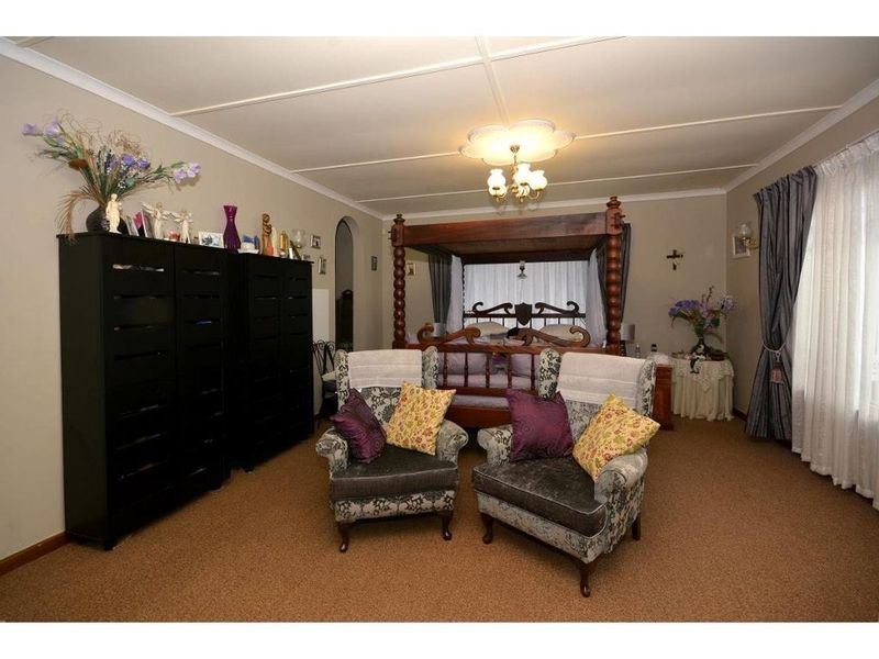 A spacious bedroom featuring neutral wall tones, carpeted flooring, and decorative ceiling detailing.
