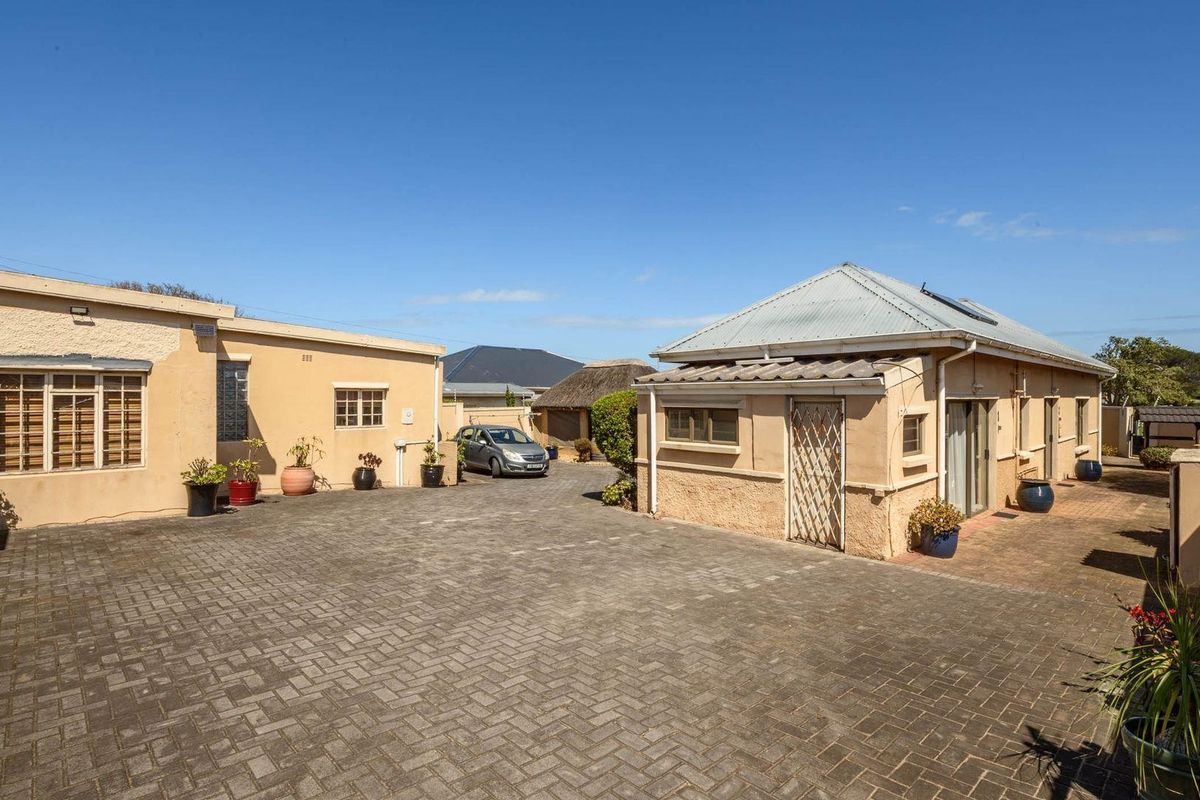 Spacious paved courtyard area between two residential structures, featuring durable block paving and access to the main building and secondary dwelling.