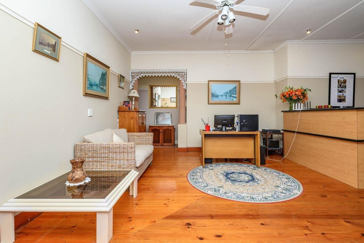 A living area featuring polished timber flooring, a decorative archway, and a built-in reception counter, suitable for a home office or reception space.