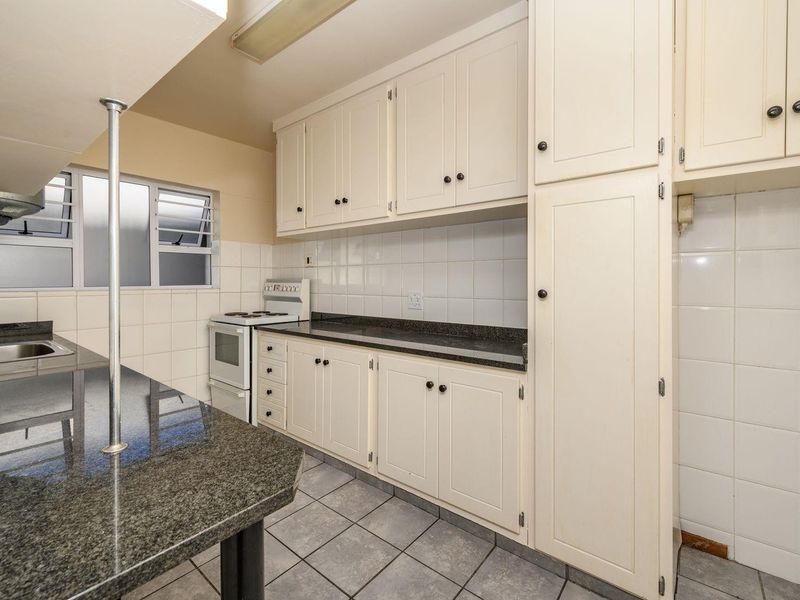 A functional kitchen featuring granite countertops, ample built-in cabinetry, tiled backsplash, and a freestanding stove, offering a clean and practical workspace.