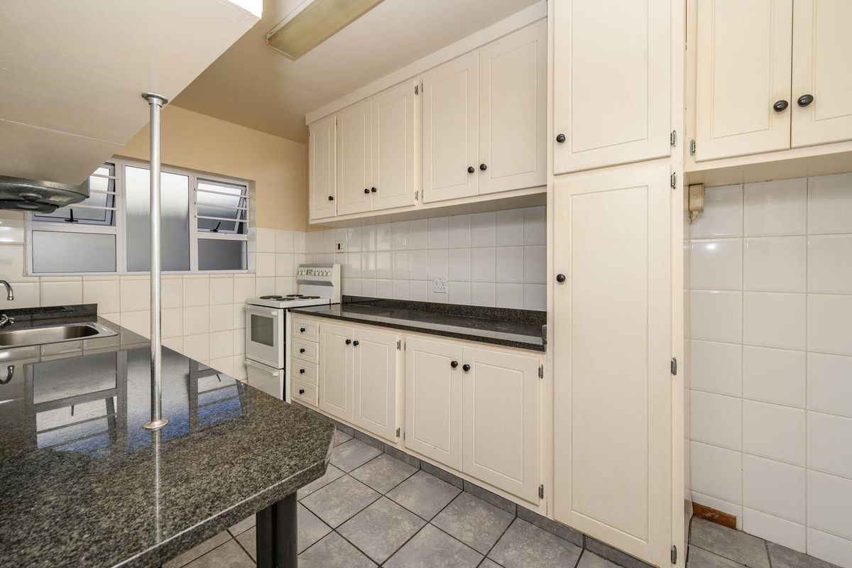 A functional kitchen featuring granite countertops, ample built-in cabinetry, tiled backsplash, and a freestanding stove, offering a clean and practical workspace.