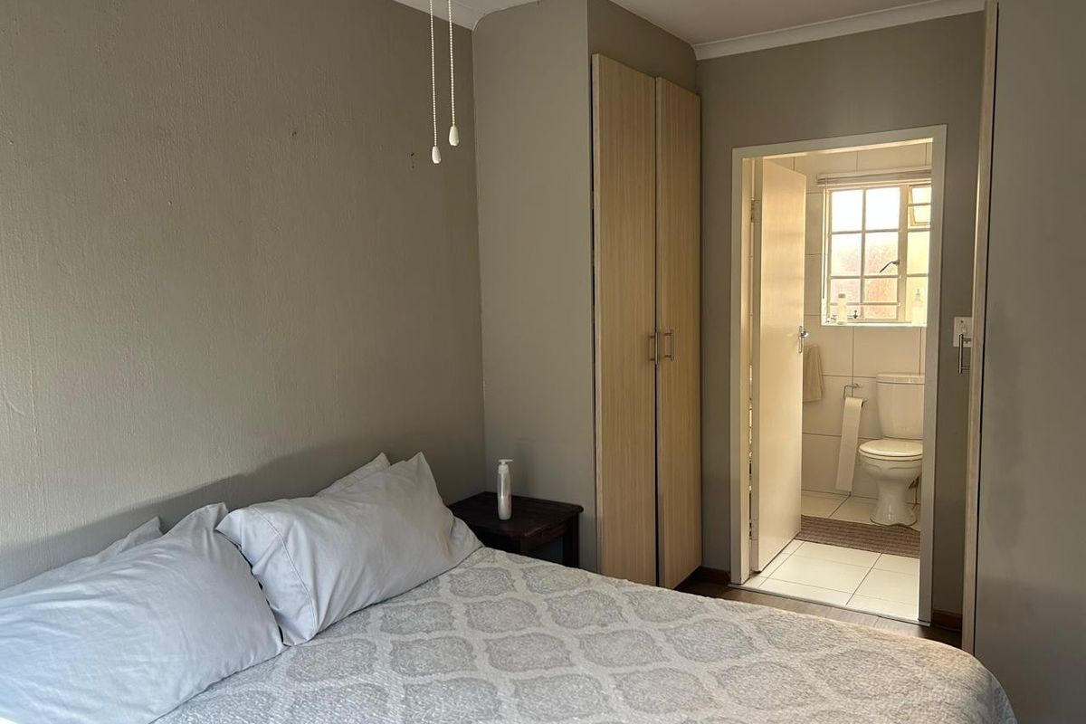 Bedroom featuring a built-in wardrobe, ceiling fan, and direct access to an en-suite bathroom with tiled flooring.