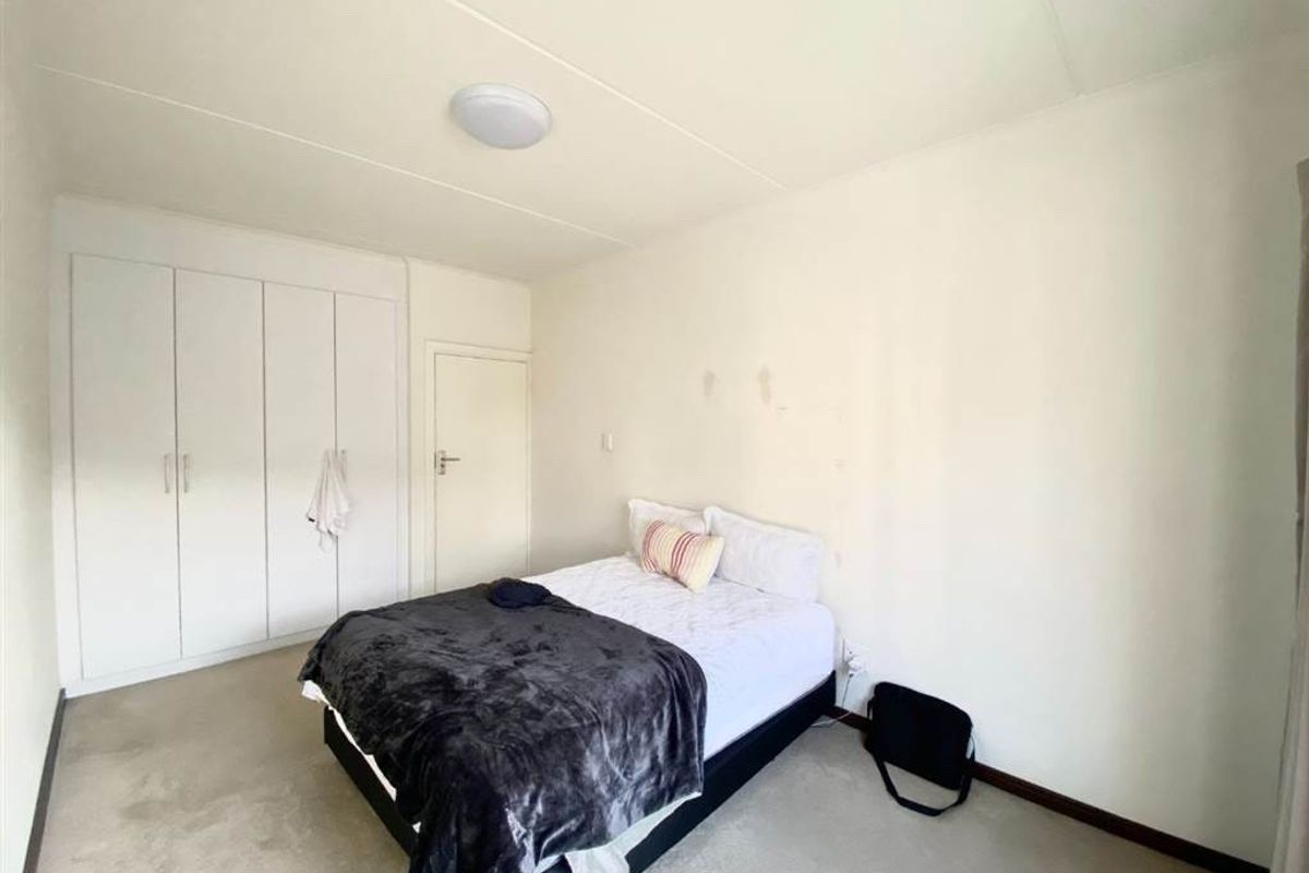 A bedroom featuring built-in floor-to-ceiling wardrobes and neutral carpeting.
