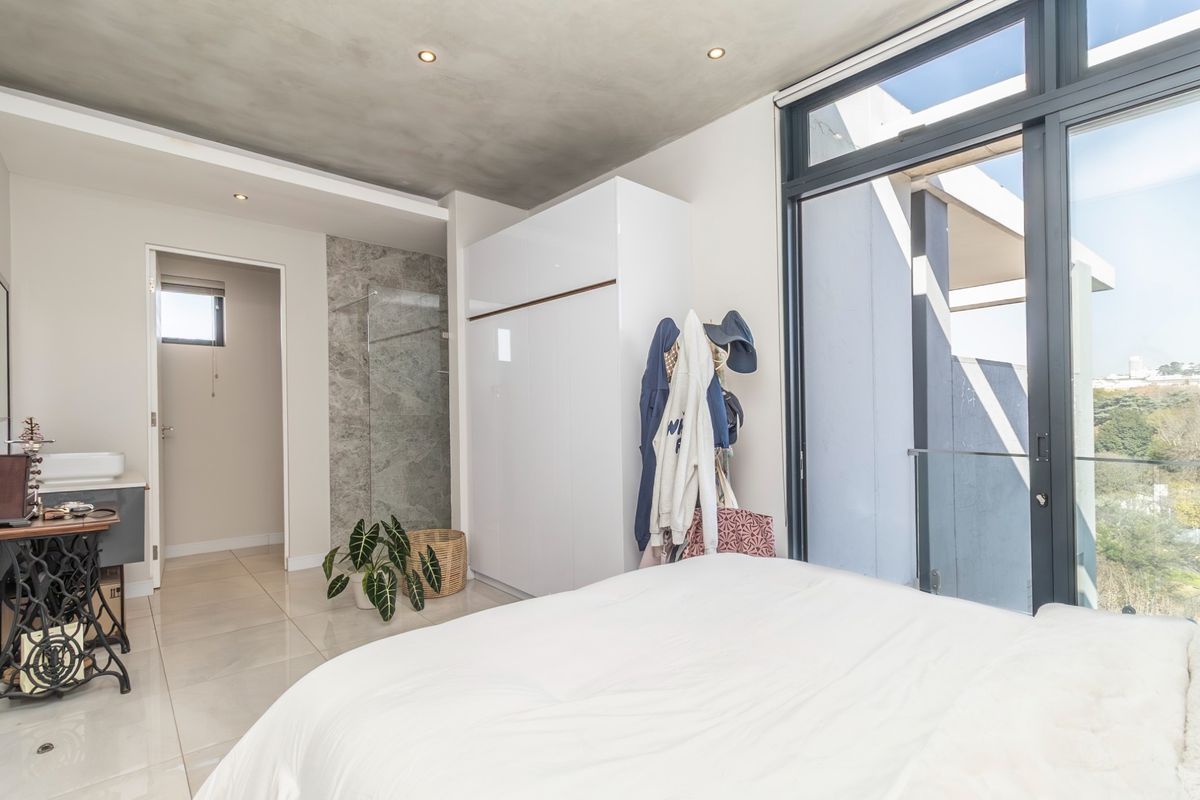 Modern bedroom featuring a sleek built-in wardrobe, polished tile flooring, and large glass sliding doors opening to a private balcony.
