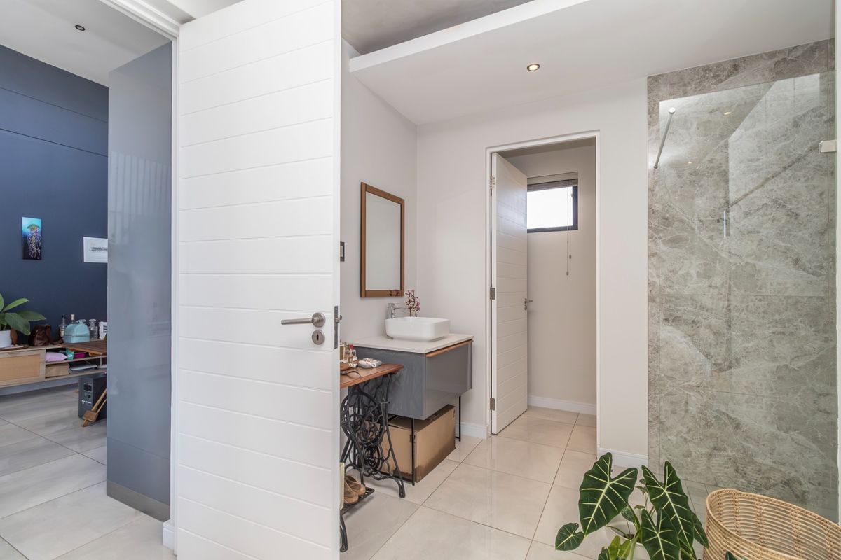 Modern bathroom featuring a floating vanity with a vessel sink, large format floor tiles, and a walk-in shower with marble-look wall tiling.