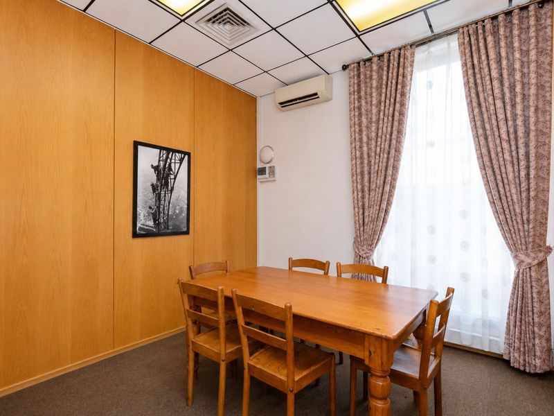 A functional office space featuring wood veneer wall paneling, a suspended ceiling with recessed lighting, and a wall-mounted air conditioning unit.