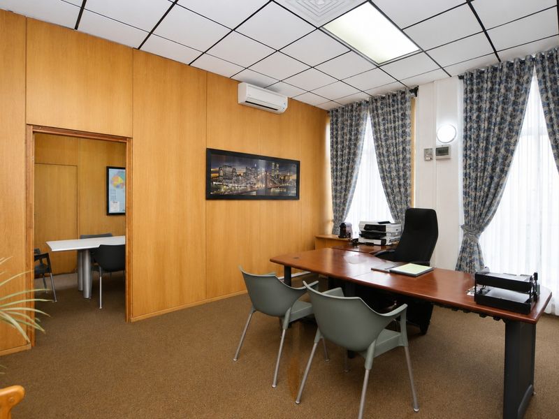 A functional commercial office space featuring wood veneer wall paneling, a suspended ceiling grid, and integrated air conditioning.