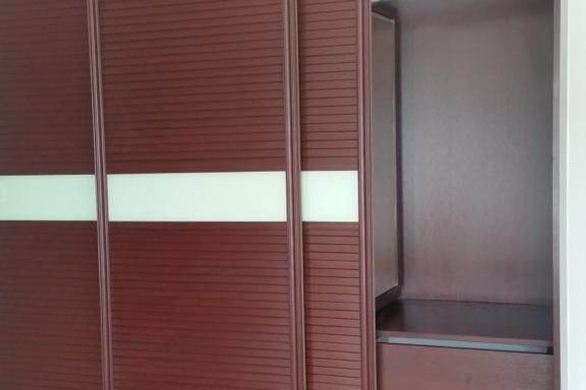 A large, built-in dark wood wardrobe featuring sliding doors with horizontal detailing and integrated internal shelving and drawer storage.