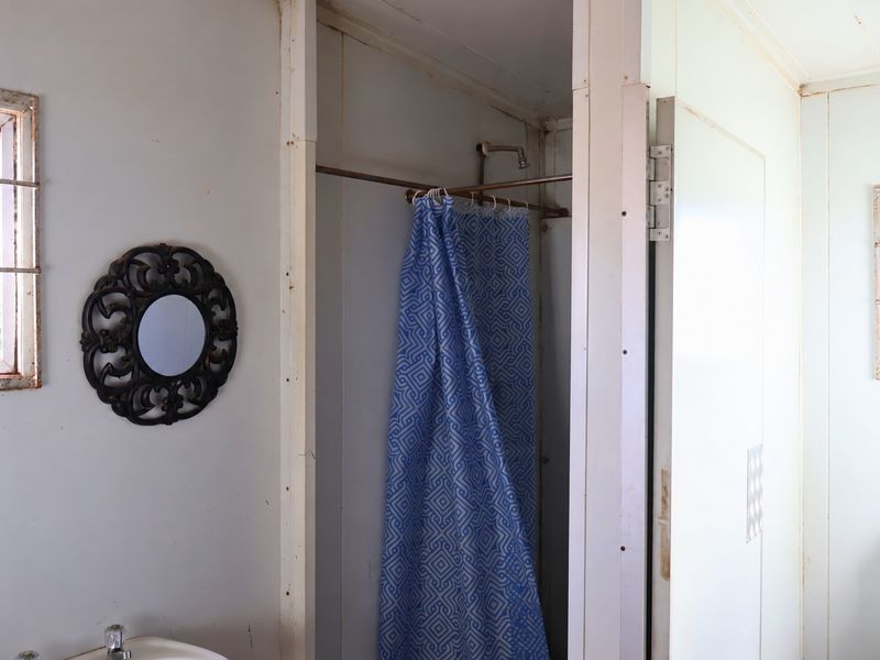 A dated bathroom featuring a shower area, toilet, and basin, showing signs of wear and requiring cosmetic updates to improve its condition.