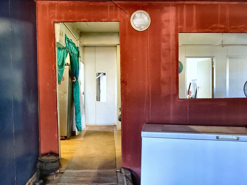 A view through a hallway showing interior wall finishes and access to adjacent rooms, requiring cosmetic updates to improve the overall aesthetic.