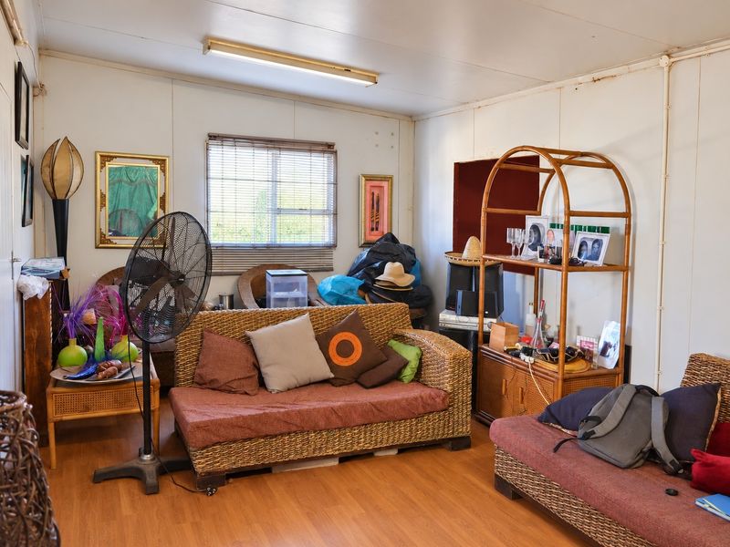 A living room featuring laminate flooring, wall paneling, and a window with venetian blinds, offering a functional space ready for modernization.
