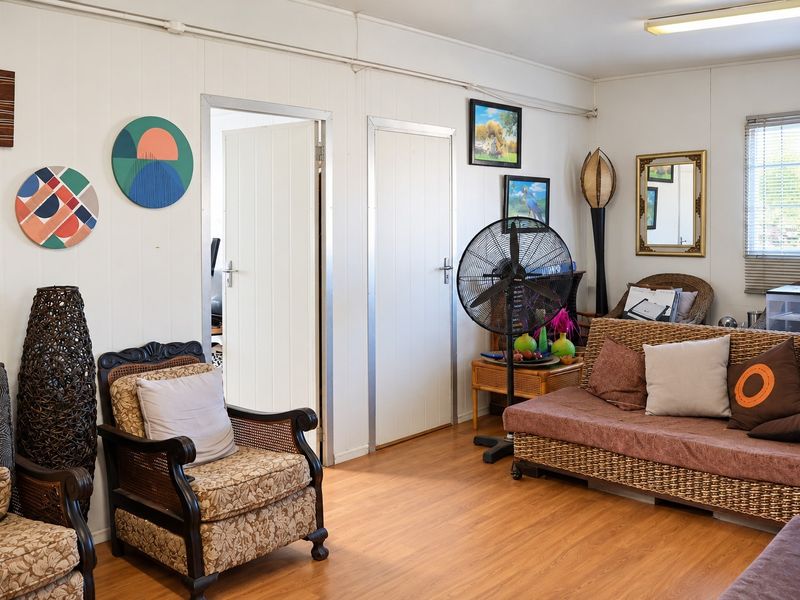 A living room featuring laminate flooring, panelled walls, and internal doors, providing a functional and neutral space for relaxation.