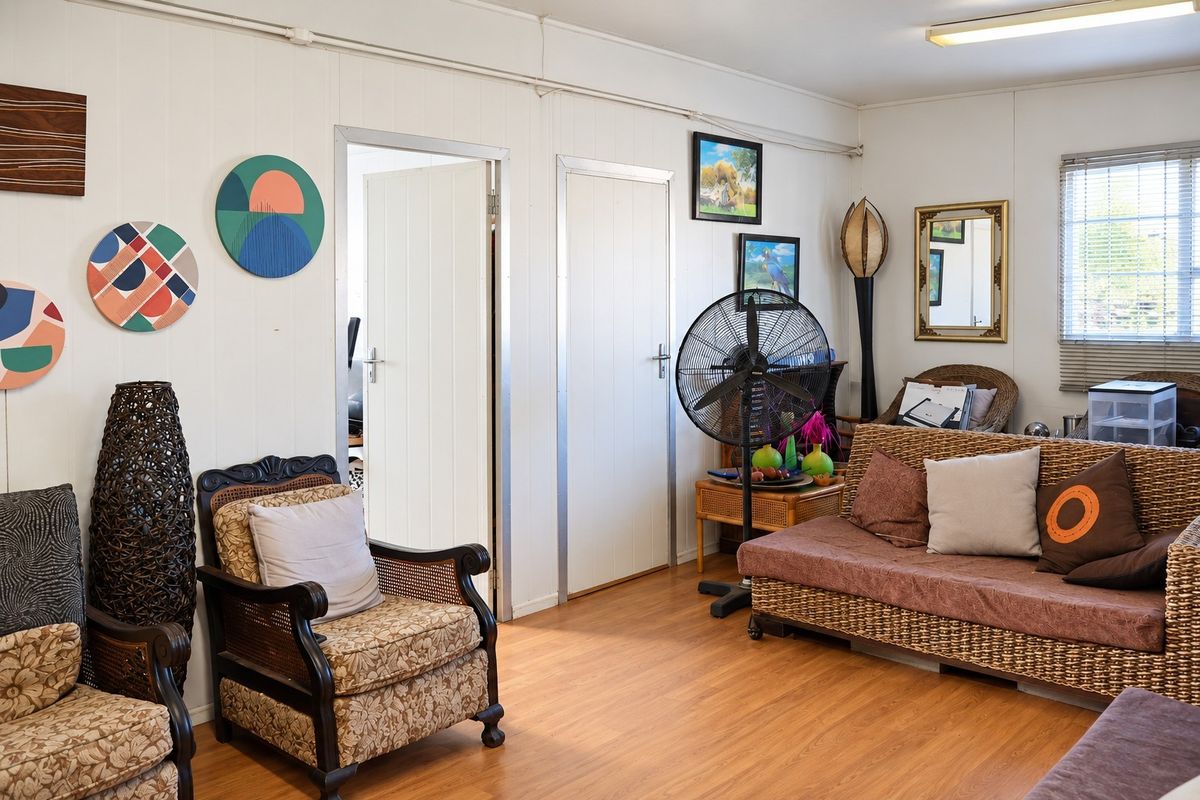 A living room featuring laminate flooring, panelled walls, and internal doors, providing a functional and neutral space for relaxation.