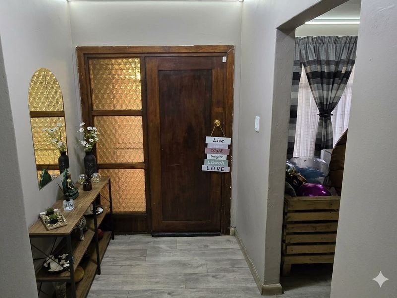 Welcoming entrance hall featuring a classic timber front door with textured glass sidelight and modern laminate flooring.