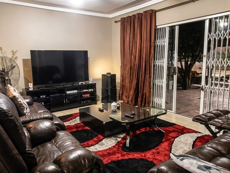 A comfortable living room featuring sliding glass doors with security gates, providing access to the outdoor area.