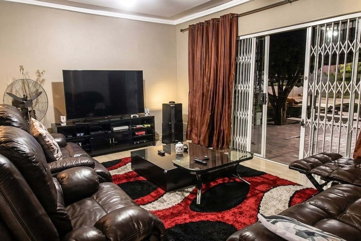 A comfortable living room featuring sliding glass doors with security gates, providing access to the outdoor area.