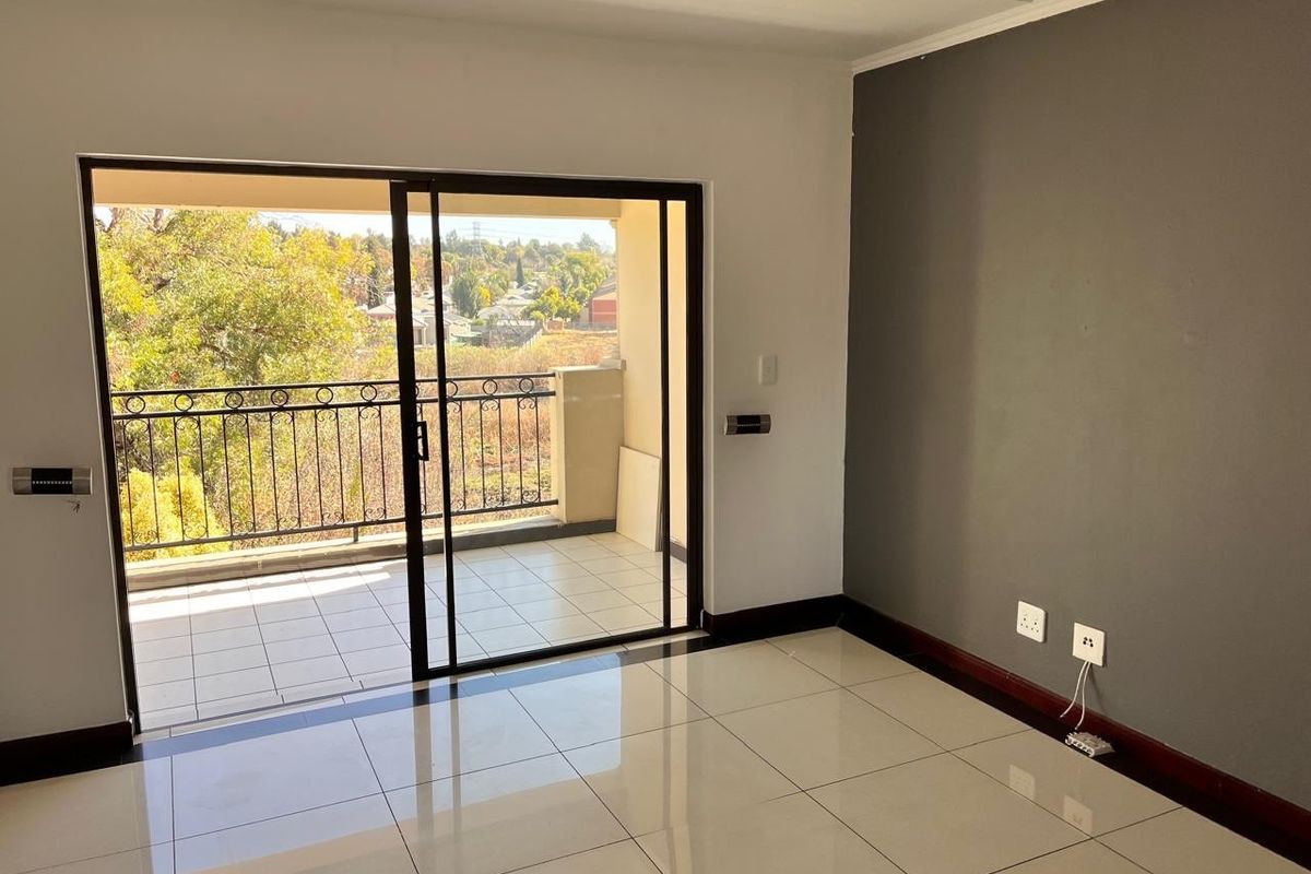 Bright living area featuring large sliding glass doors that open onto a private balcony with scenic views and tiled flooring throughout.