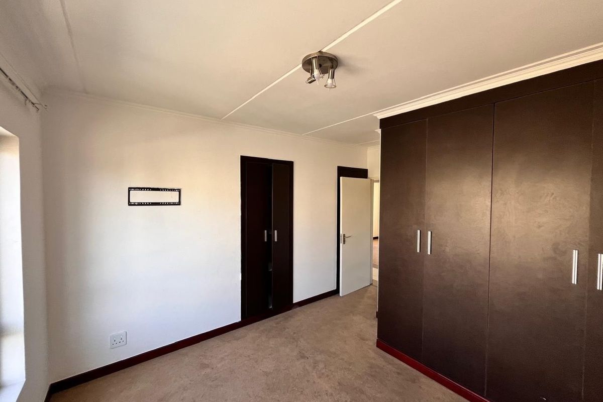 A bedroom featuring built-in dark wood cabinetry, neutral walls, and carpeted flooring, offering functional storage space.