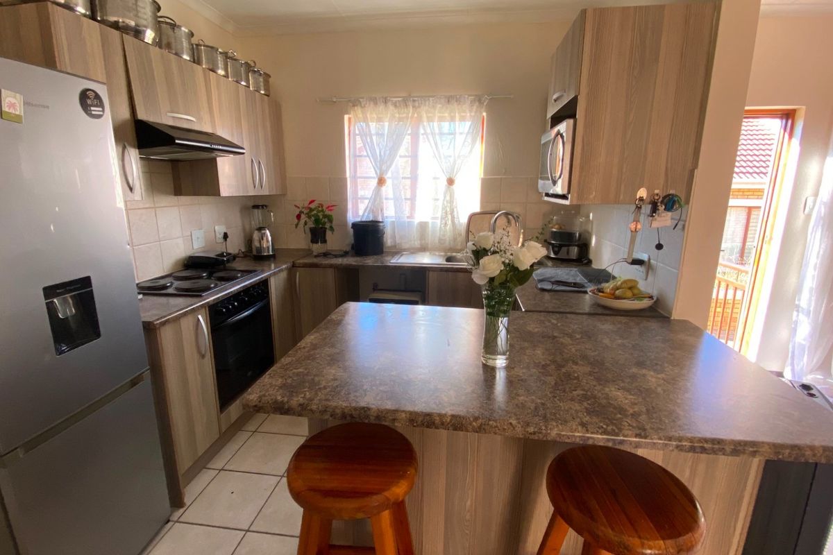 Functional kitchen featuring laminate cabinetry, built-in oven, electric hob, extractor fan, and a breakfast nook with tiled flooring and backsplash.