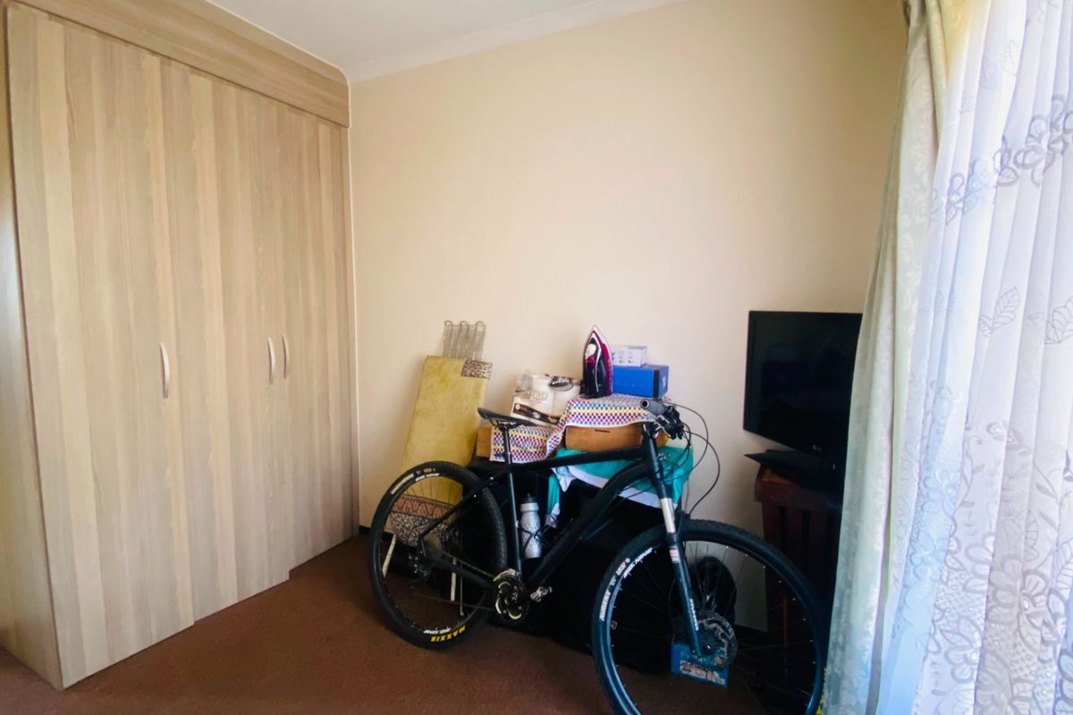 A bedroom featuring neutral walls, carpeted flooring, and a large built-in wardrobe with wood-grain finish doors.