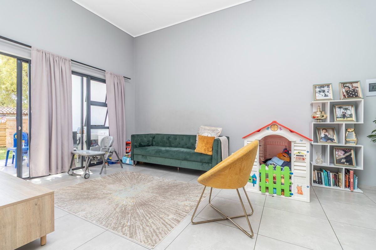 A bright living room featuring large sliding glass doors that provide access to an outdoor area, complemented by neutral tiled flooring.