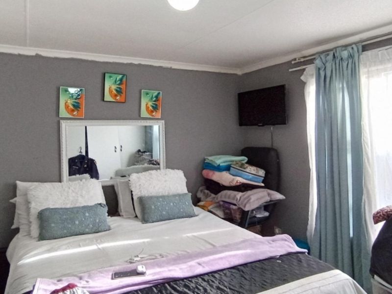A bedroom featuring grey painted walls, a built-in wardrobe, and a window with curtain tracks.