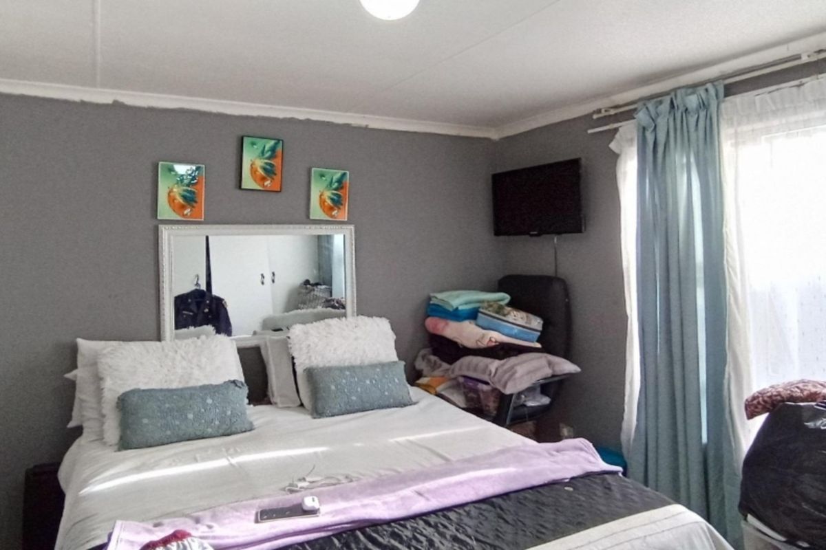 A bedroom featuring grey painted walls, a built-in wardrobe, and a window with curtain tracks.