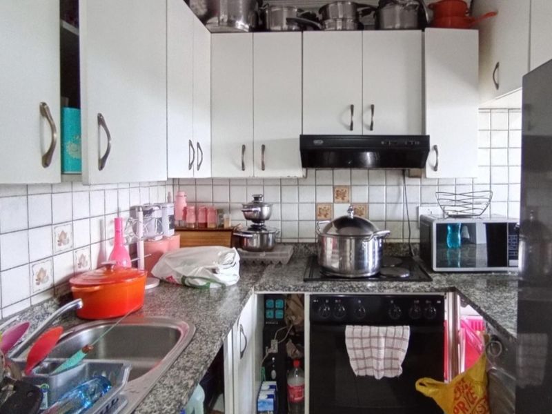 A functional kitchen featuring granite countertops, white cabinetry, a built-in oven with extractor fan, and a stainless steel sink.