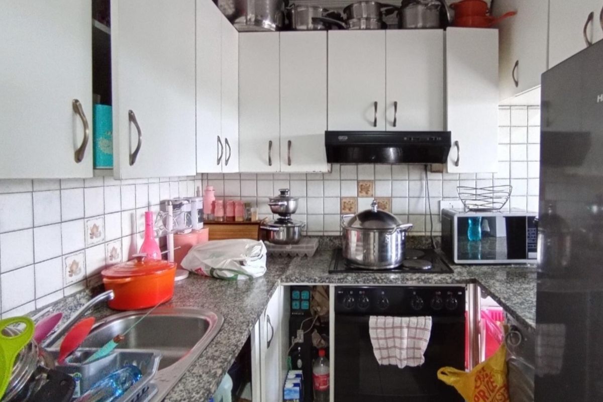 A functional kitchen featuring granite countertops, white cabinetry, a built-in oven with extractor fan, and a stainless steel sink.