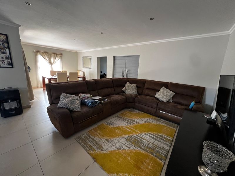 Spacious open-plan living and dining area featuring neutral tiled flooring, recessed downlighting, and a seamless flow between the lounge and dining space.