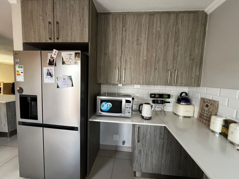 Modern kitchen featuring wood-grain cabinetry, white subway tile backsplash, and stone-look countertops, providing a clean and functional workspace.