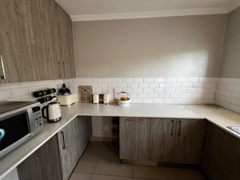 Modern kitchen featuring wood-grain cabinetry, white quartz countertops, and a classic white subway tile backsplash.