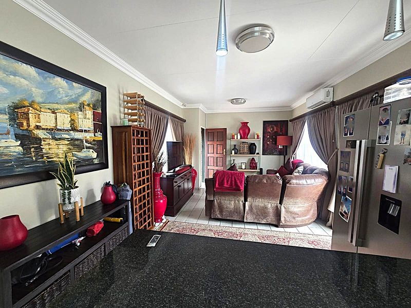 Open-plan living area featuring tiled flooring, crown molding, and a granite kitchen countertop, creating a functional and connected space.