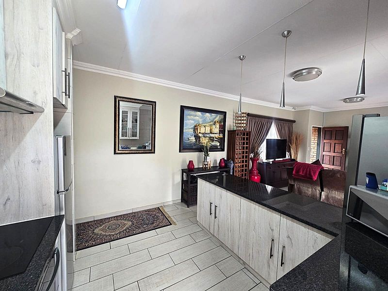 Spacious open-plan living area featuring a modern kitchen with granite countertops, island seating, and tiled flooring, seamlessly flowing into the lounge space.