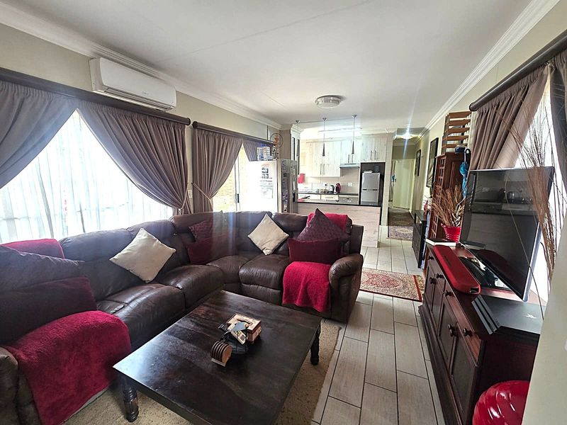 Open-plan living area featuring tiled flooring, split-system air conditioning, and a connected kitchen space with built-in cabinetry.