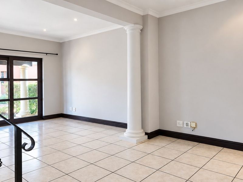A bright, empty living area featuring neutral tiled floors, a decorative column, and a sliding glass door leading to the exterior.